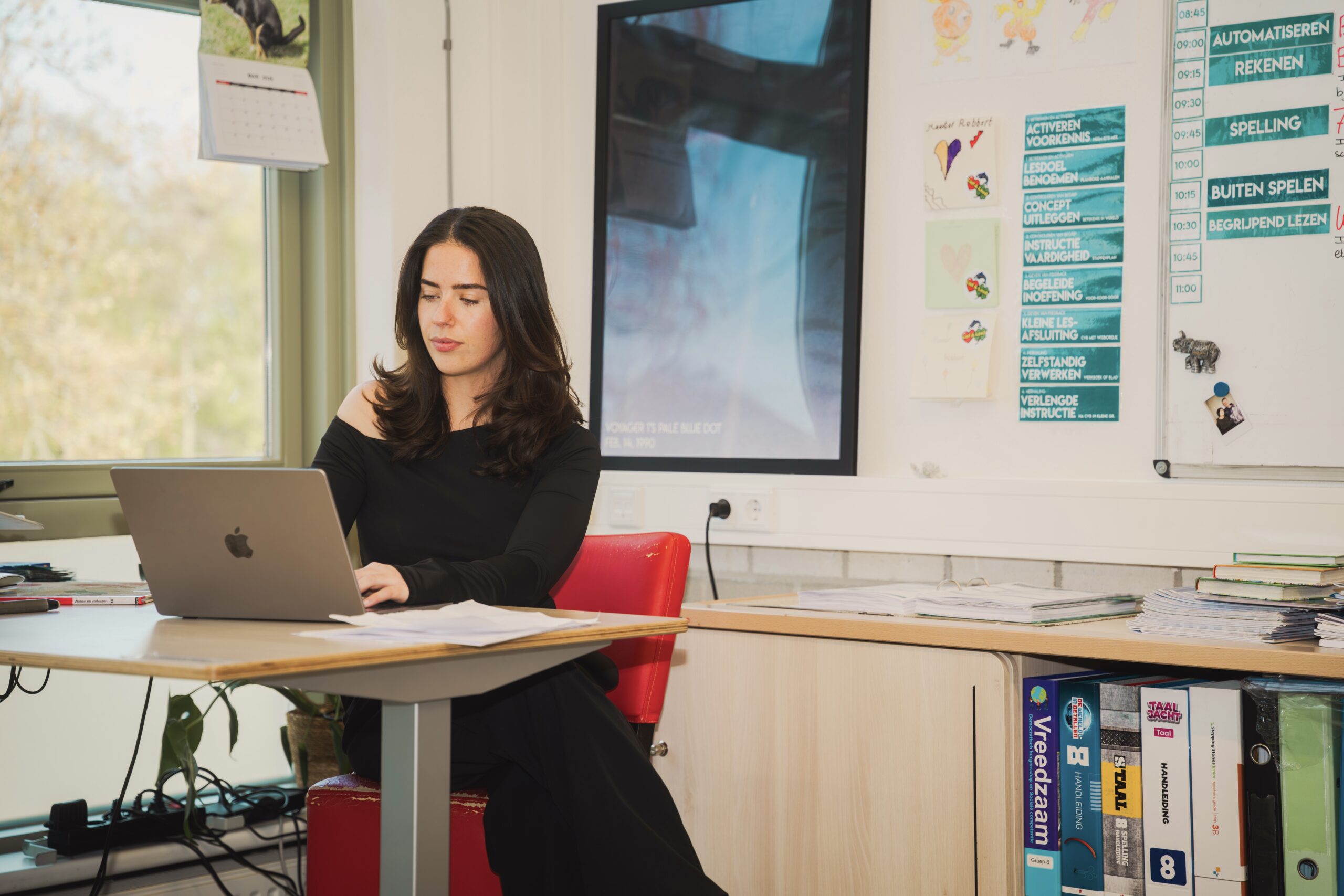 Docent werkt op haar laptop in het klaslokaal